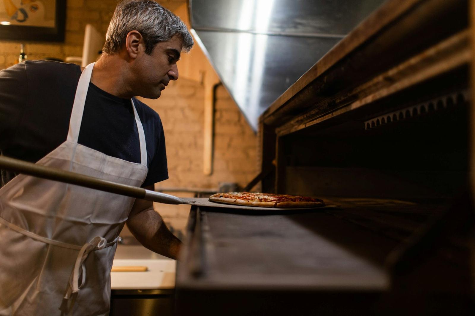 Pizzar punând o pizza în cuptor